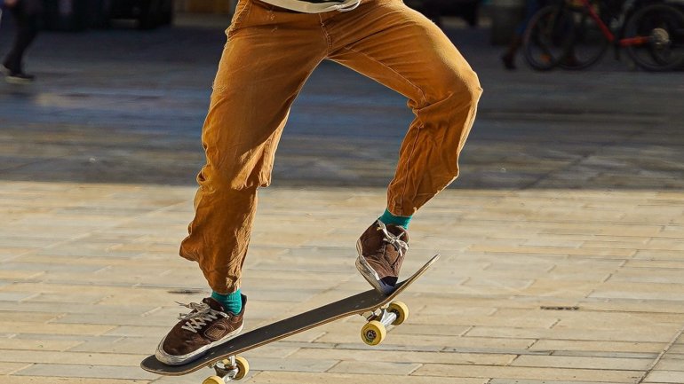 Cames d'un noi que salta sobre un skate pel carrer