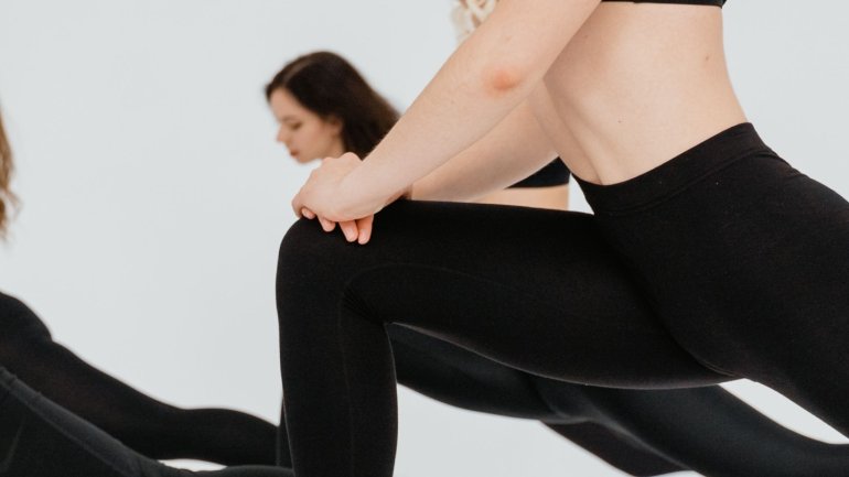 Dones amb roba esportiva negra que estan fent pilates en grup