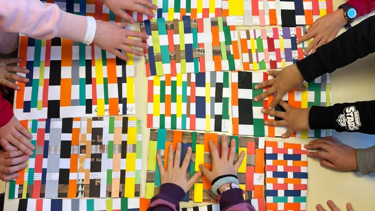 Unes mans fent un teixit amb tires de paper de colors