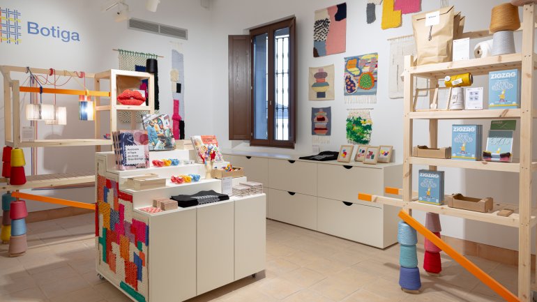 Botiga del Centre Grau-Garriga d'Art Tèxtil Contemporani, es veuen llibres, tapissos i altres elements per adquirir.