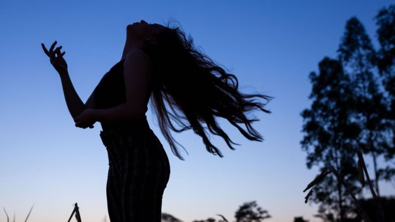 L'ombra d'una dona jove ballant en la naturalesa
