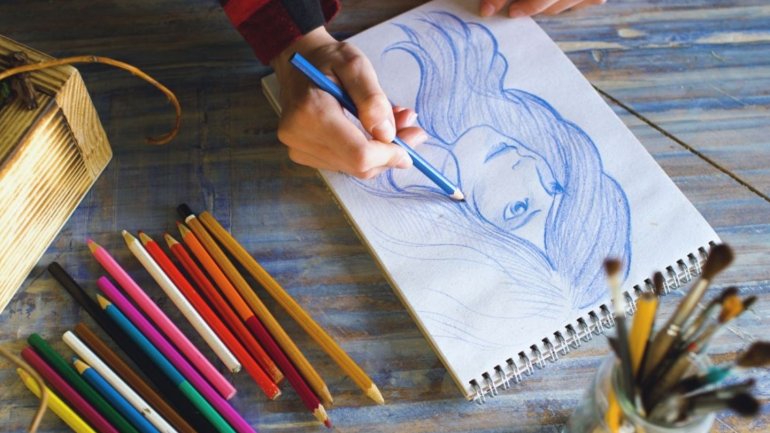 Unes mans dibuixant en una fulla amb llapis de colors
