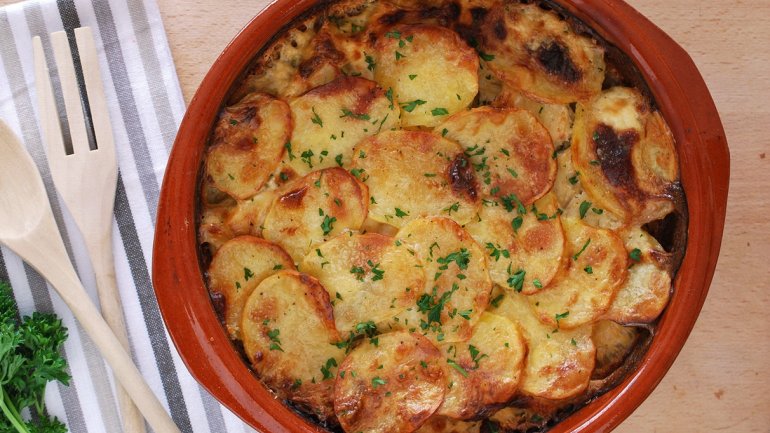 Gratinat de patata al forn amb làmines de patata daurades, servit en una cassola de fang.