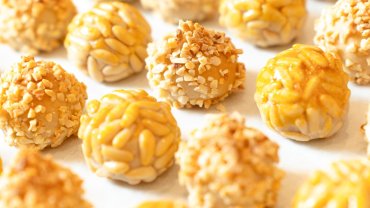 Panellets de pinyons i d'ametlla sobre una safata, amb acabat daurat i brillant.