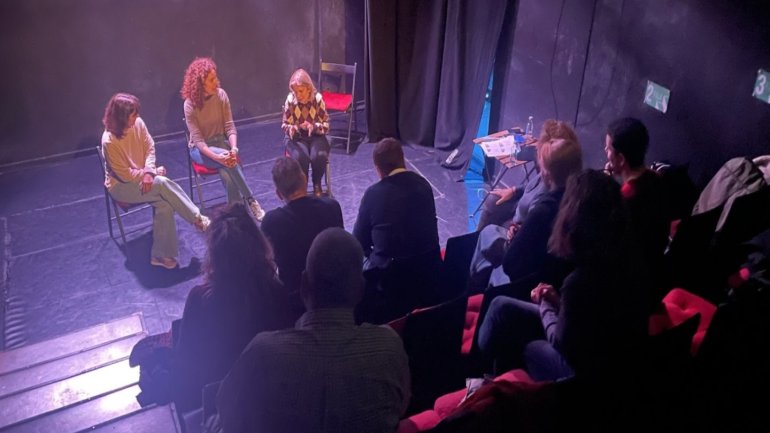 grup de tatre amb tres persones a l'escenari i la resta de públic 