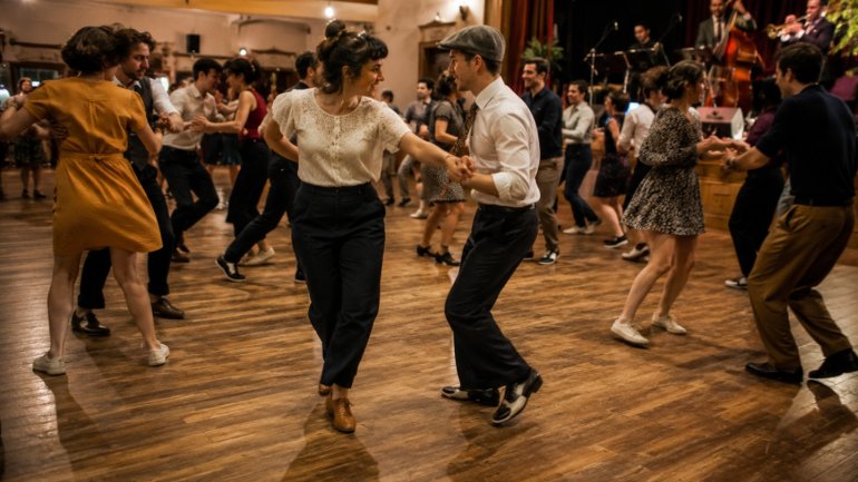 Grup de persones ballant en parella en una sala amb música en directe i ambient festiu.