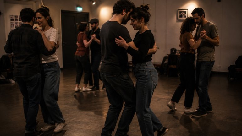 Diverses parelles practiquen ball en una sala de dansa, movent-se agafades en un ambient tranquil i concentrat. L’espai està il·luminat amb llum càlida i mostra una sessió de ball social.