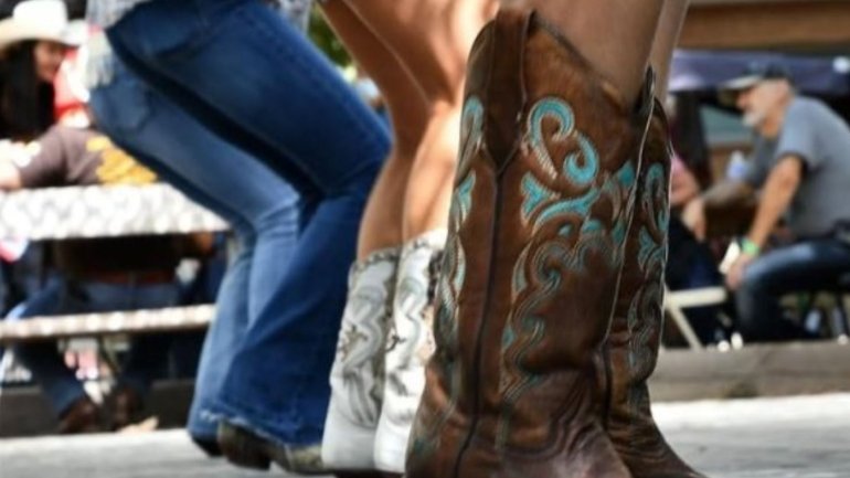 Participants ballant country amb botes de cowboy en una activitat de grup a l'aire lliure