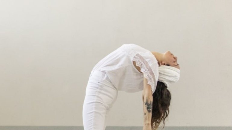 Persona practicant kundalini ioga amb una postura d'extensió cap enrere en un espai interior